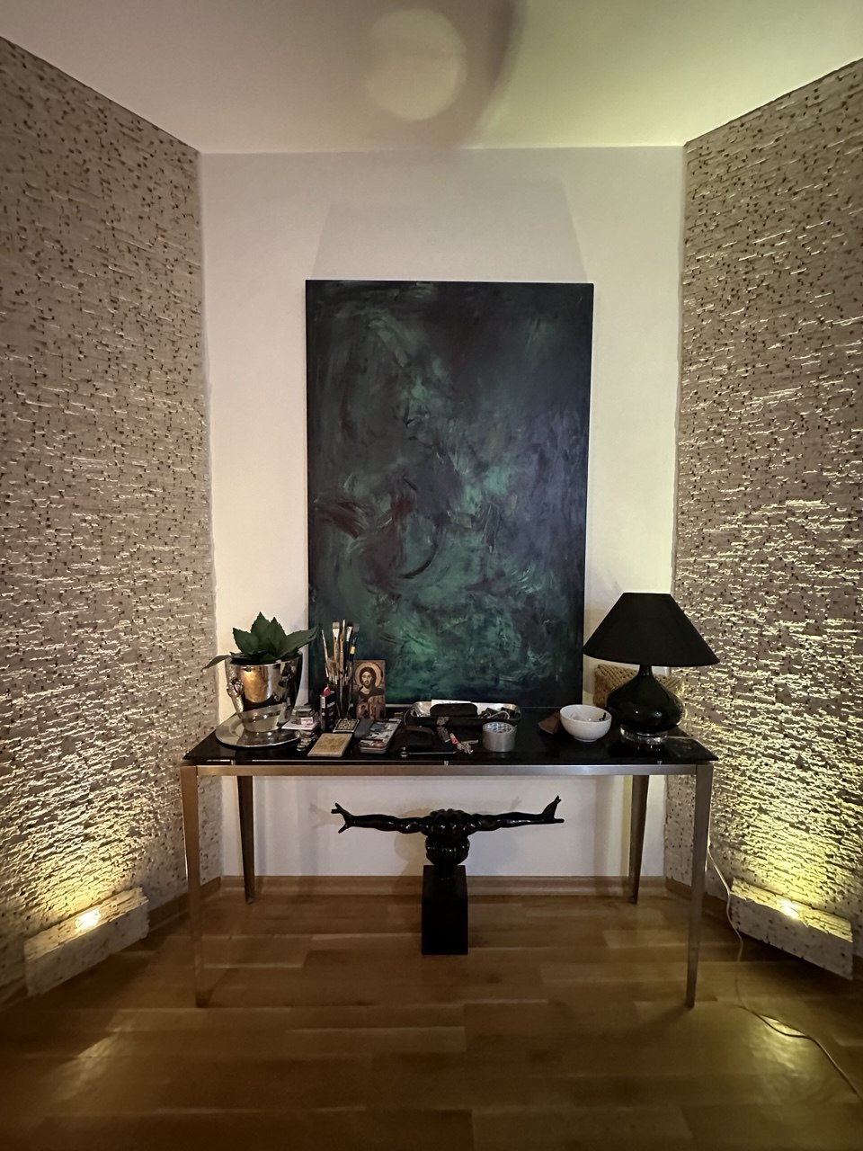 Dark green abstract painting hung above a console table in an interior